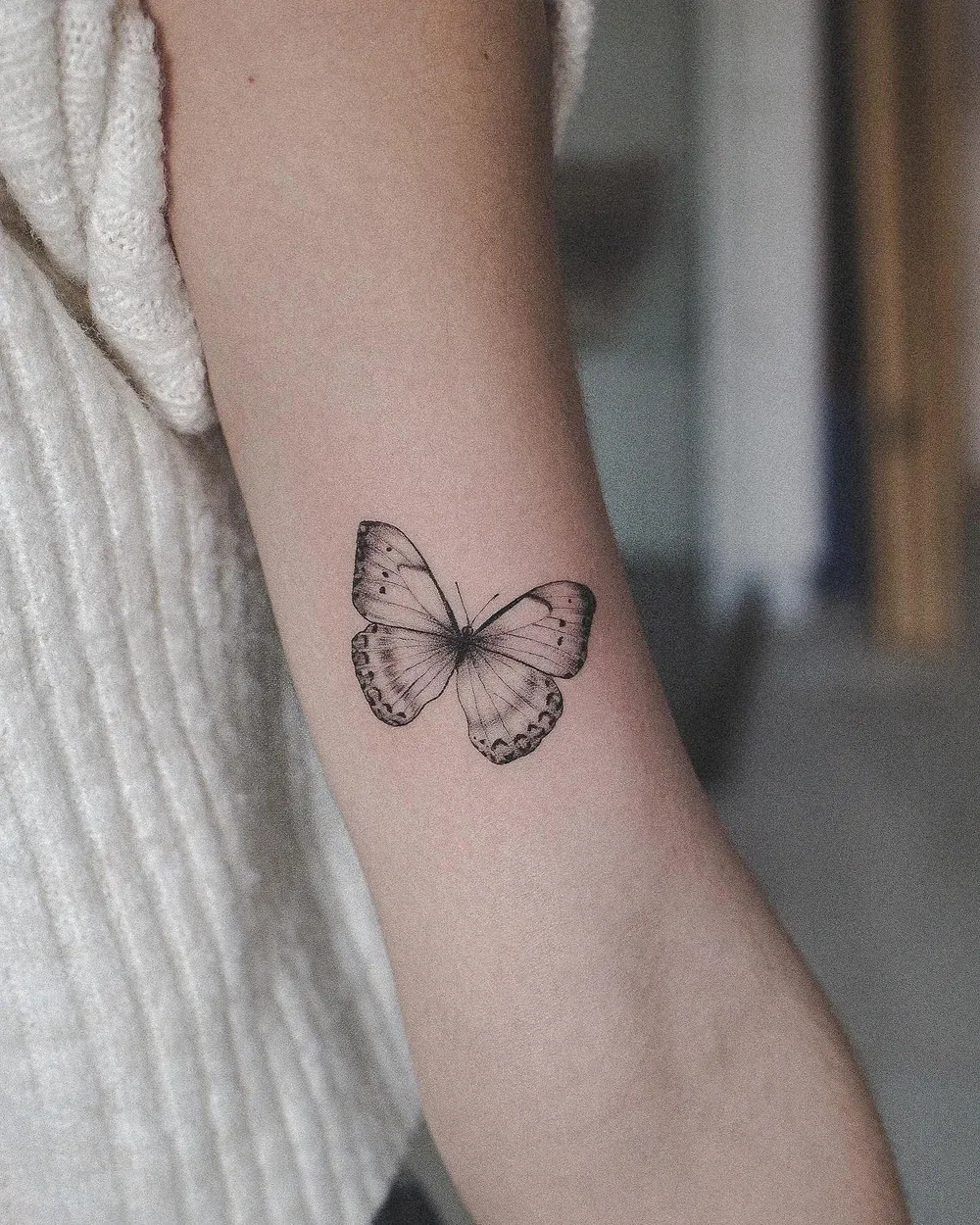 Kleines Schmetterling-Tattoo am Oberarm — ein typisches erstes Tattoo, gestochen bei LAKIMII Berlin