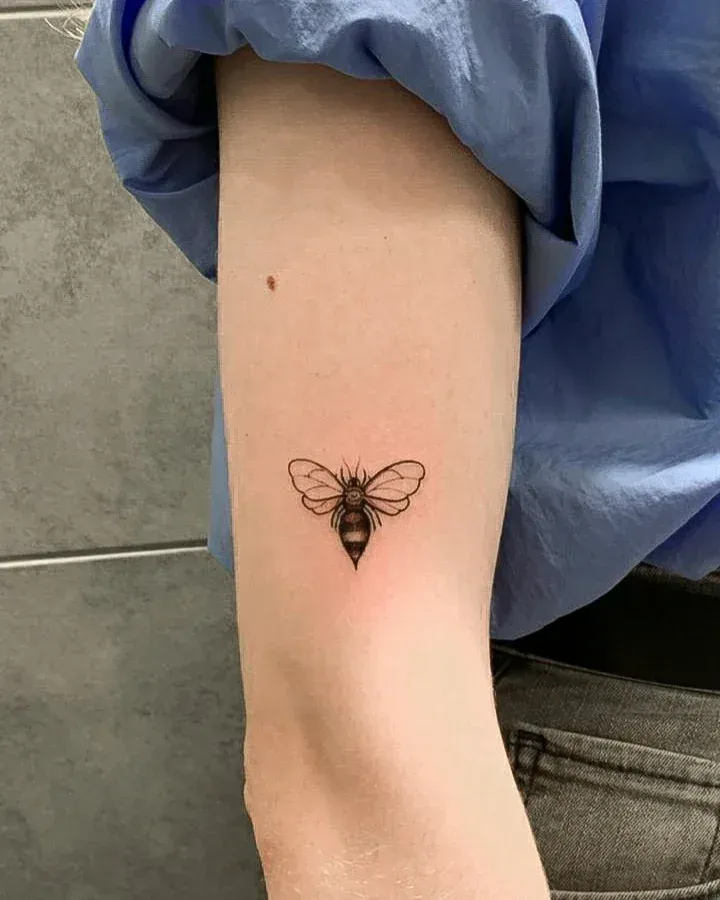 Kleines Bienen-Tattoo am Oberarm — typisches spontanes Walk-in-Motiv aus dem LAKIMII Studio Berlin
